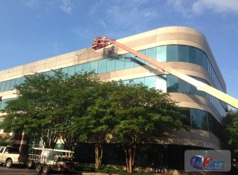Commercial building facade being pressure washed from a lift