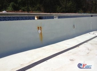 Swimming pool surface with rust stain before pressure washing