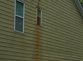 Dirty vinyl house siding with stains before pressure washing